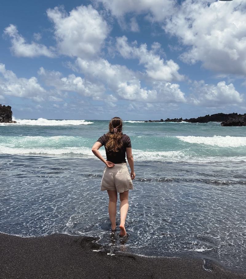 Woman wading into the surf on a black sand beach