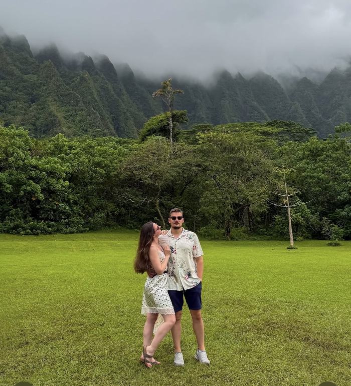 Couple standing together in front of misty green mountains