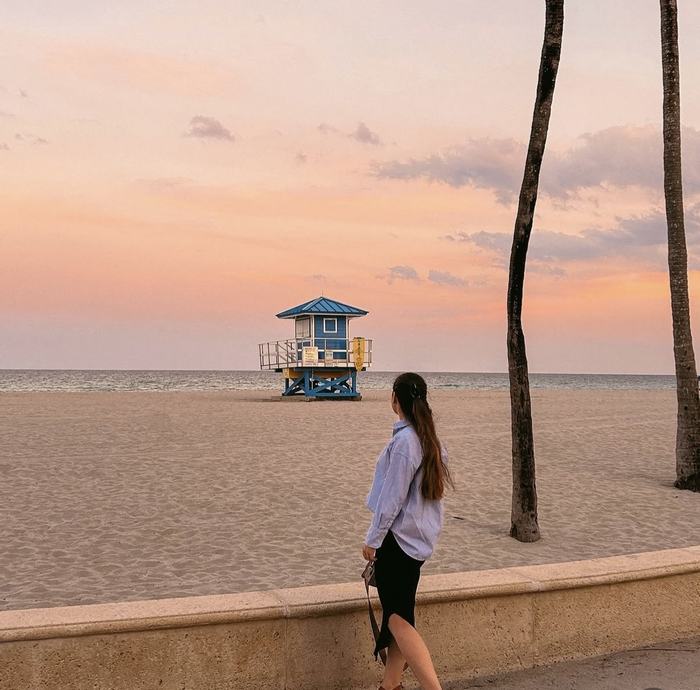 Woman walking along a beach promenade at sunset
