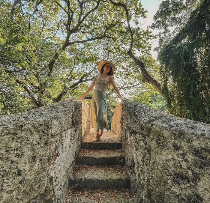 Woman standing at the top of old stone steps under trees